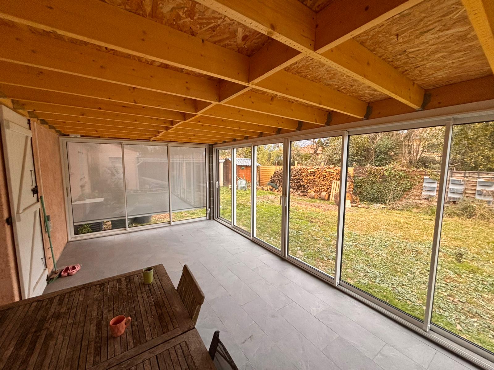 photo d'une terrasse fermée par des baies vitrées et installation d'un store