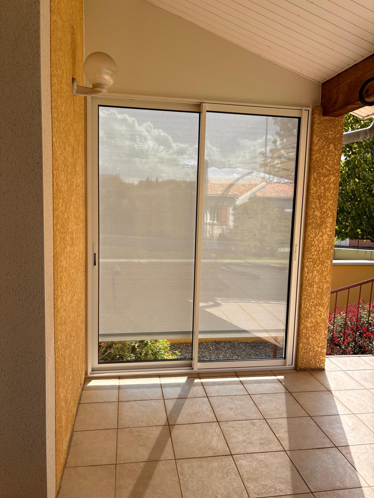 Vue de l'intérieur du coulissant installé pour fermer une partie d'une terrasse avec un store