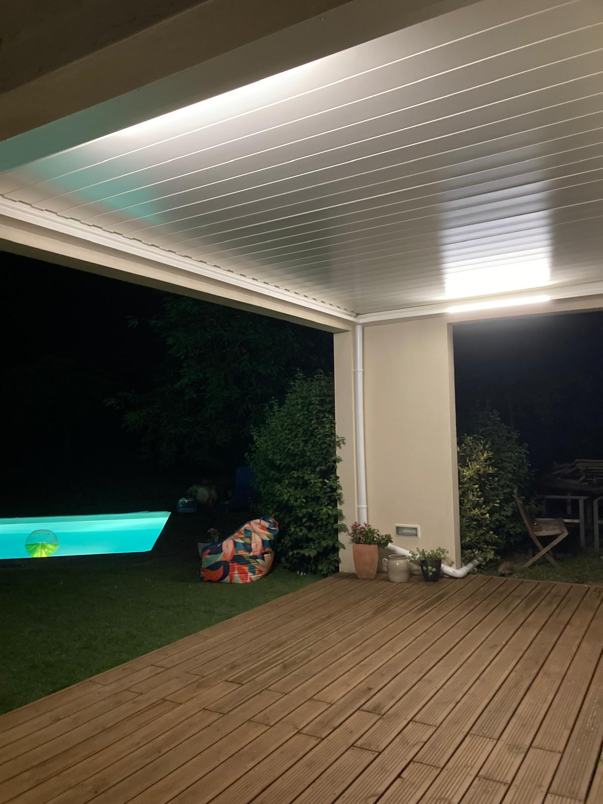vue de nuit d'une pergola bioclimatique avec lames fermées installée entre des murs à Toulouse par Occ'Fermetures