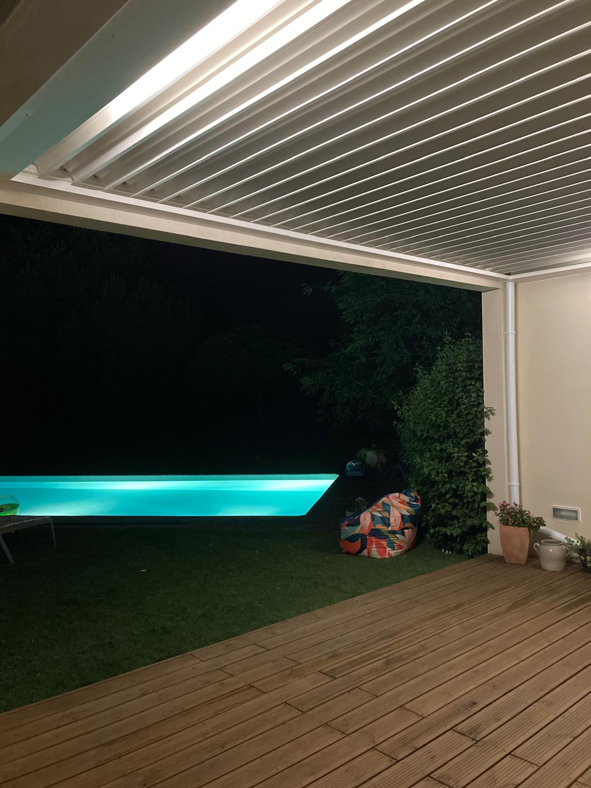 vue de nuit avec éclairage led d'une pergola bioclimatique avec lames ouvertes, installée entre des murs à Toulouse par Occ'Fermetures