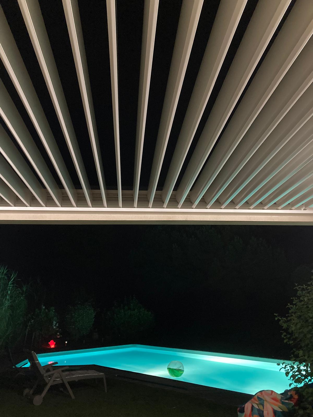 vue de nuit d'une pergola bioclimatique avec lames ouvertes, installée à Toulouse par Occ'Fermetures
