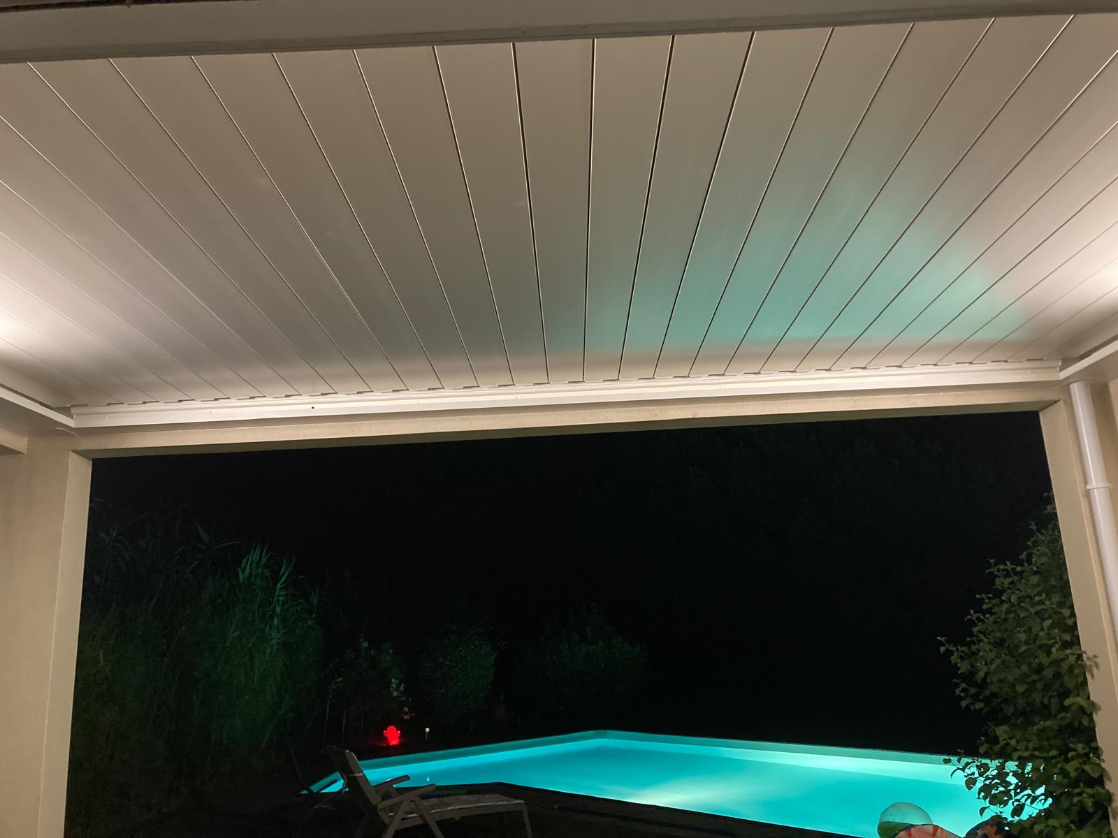 vue de nuit d'une pergola bioclimatique avec lames fermées installée entre des murs à Toulouse par Occ'Fermetures