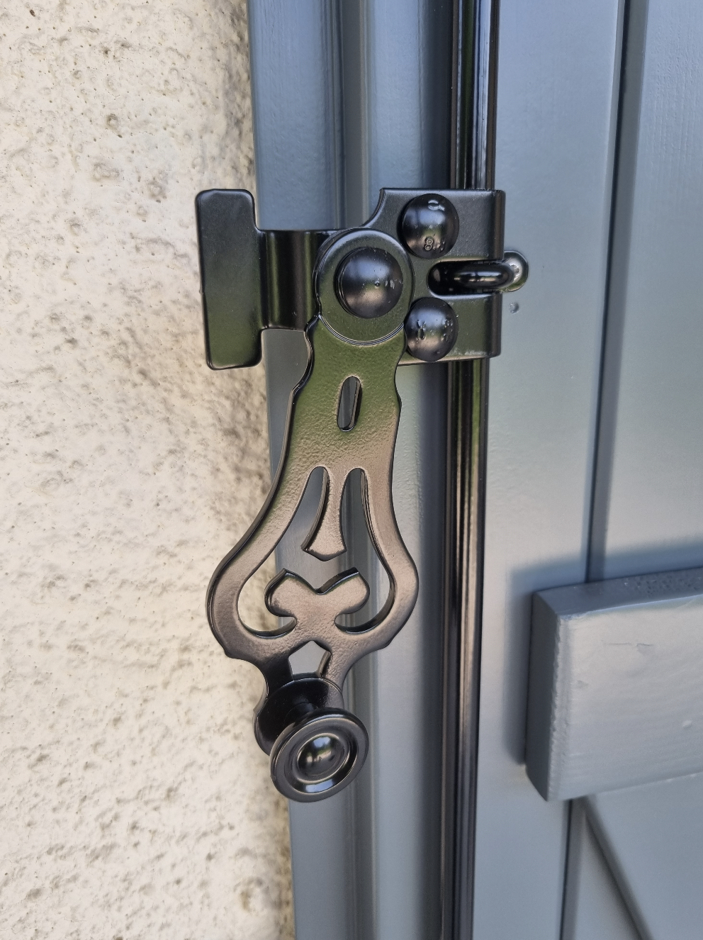 photo zoom sur un détail des volets en bois, accroche en métal noir